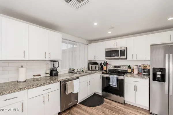 a kitchen with stainless steel appliances granite countertop a sink and white cabinets