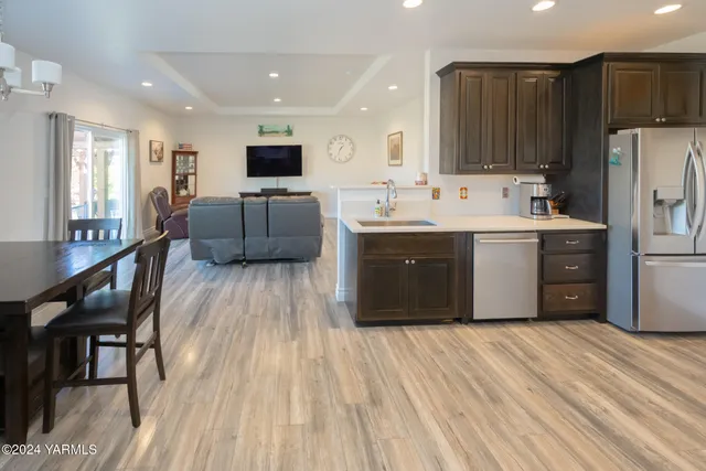 a large kitchen with stainless steel appliances a stove a sink dishwasher a refrigerator oven and a dining table with wooden floor