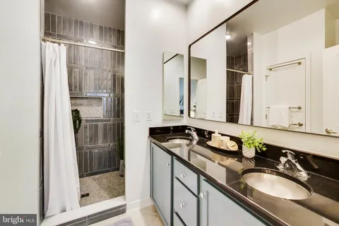 a bathroom with a granite countertop sink a mirror and shower