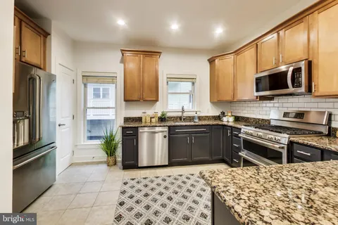 a kitchen with stainless steel appliances granite countertop a refrigerator stove top oven and sink