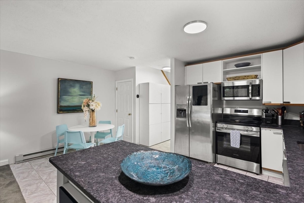 84 Round House Road, Unit 84 Bourne, MA 02532 - Photo 7 of 33 a kitchen with stainless steel appliances granite countertop a sink a stove a microwave a dining table and chairs