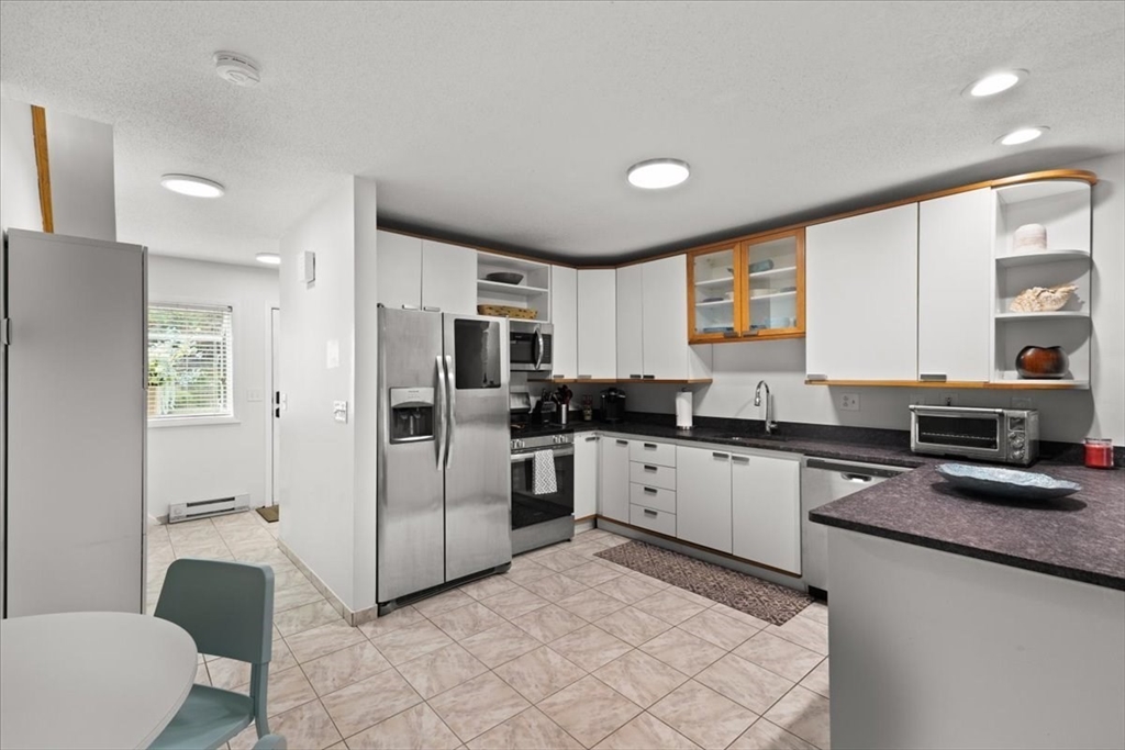 84 Round House Road, Unit 84 Bourne, MA 02532 - Photo 9 of 33 a kitchen with white cabinets and stainless steel appliances