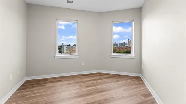 an empty room with wooden floor and windows