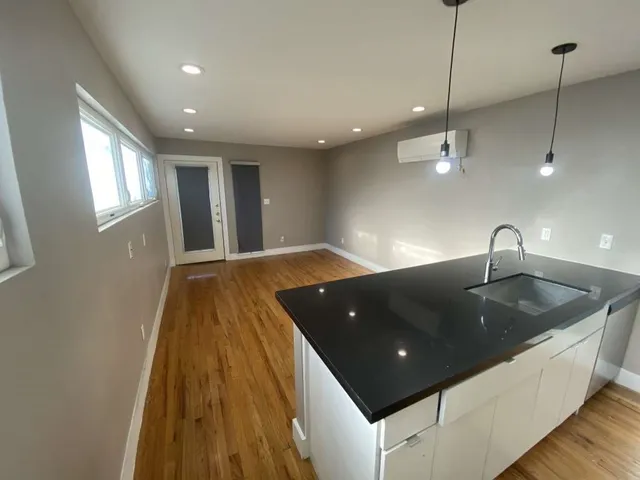 a large hall with stainless steel appliances granite countertop a sink a large window and a fireplace