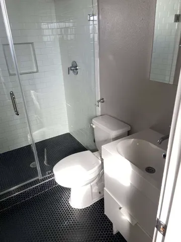a white toilet sitting next to a bathroom sink and a shower