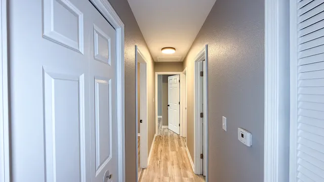 a view of a hallway with wooden floor and a bathroom