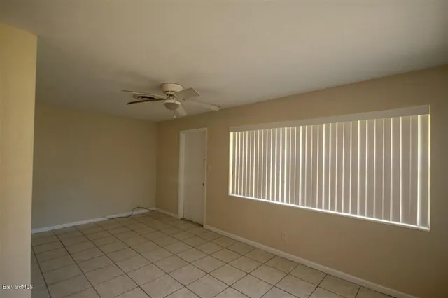 an empty room with a ceiling fan and window