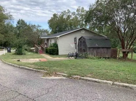 a backyard of a house with plants and large tree