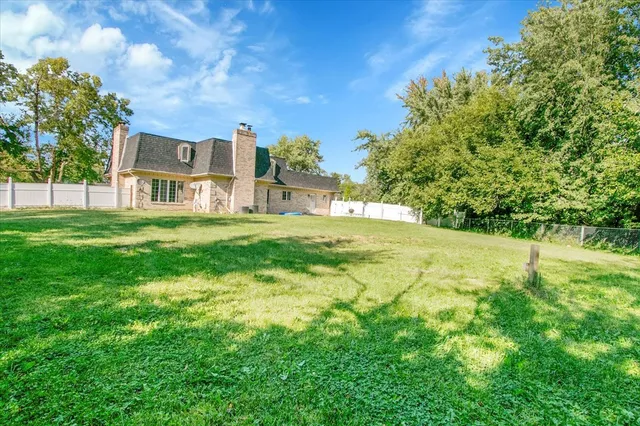 a view of a house with a big yard and large trees