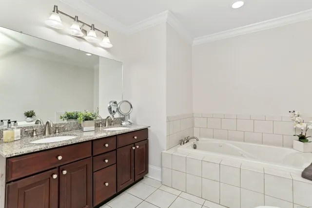 a bathroom with a tub a double vanity sink and mirror