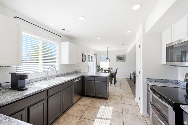 5485 Heather Way Tooele, UT 84074 - Photo 20 of 41 Open-concept kitchen with white upper cabinetry, dark base cabinetry, light-toned tile flooring, and speckled countertops