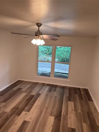 a view of a room with wooden floor a ceiling fan and window