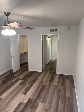 a view of a room with wooden floor closet and a ceiling fan