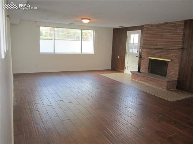 823 Cresta Road Colorado Springs, CO 80905 - Photo 24 of 36 Lower level features an oversized Rec/Family Room area with wood burning fireplace (hard to find in today's construction), hearth, and walkout to backyard. That beautiful hardwood floor is actually tile, for easy maintenance!