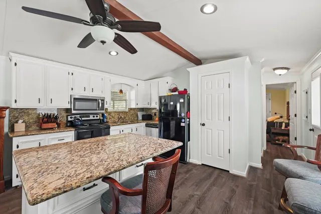 a kitchen with stainless steel appliances kitchen island granite countertop a table chairs in it and wooden floors