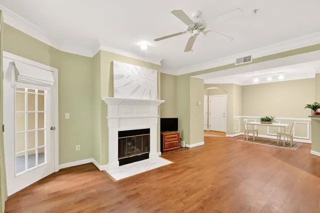 a view of a livingroom with a fireplace a ceiling fan and windows