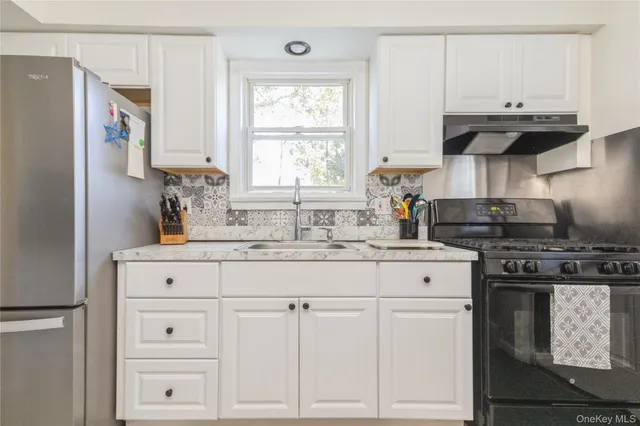 a kitchen with granite countertop white cabinets and stainless steel appliances