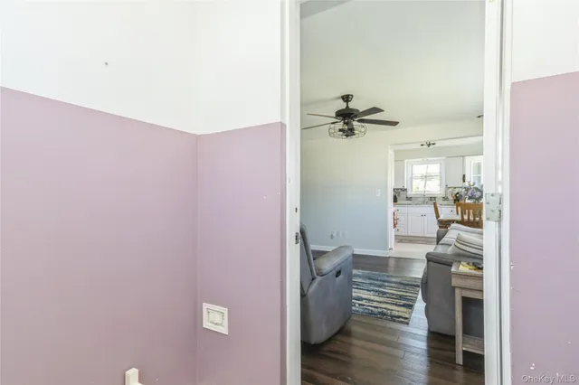 a view of a hallway with wooden floor and a living room