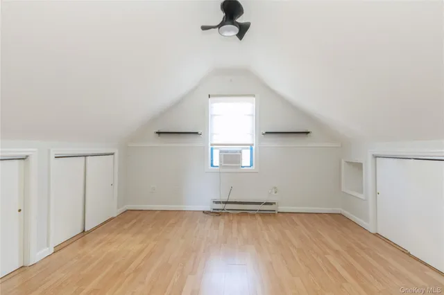 an empty room with wooden floor cabinet and windows