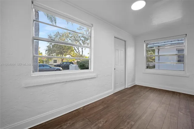 an empty room with wooden floor and windows