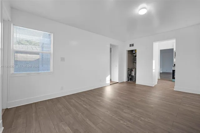 a view of an empty room with wooden floor and a window