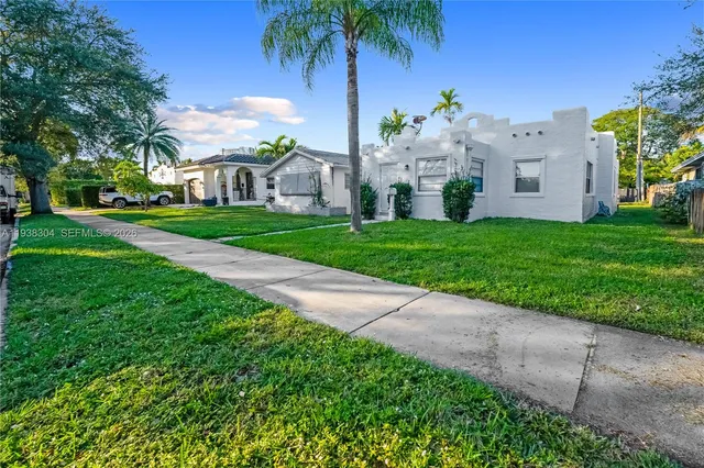 a view of a white house with a yard and potted plants