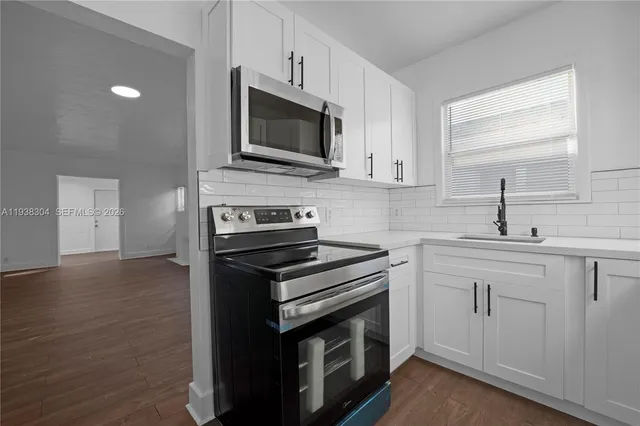 a kitchen with cabinets stainless steel appliances and wooden floor