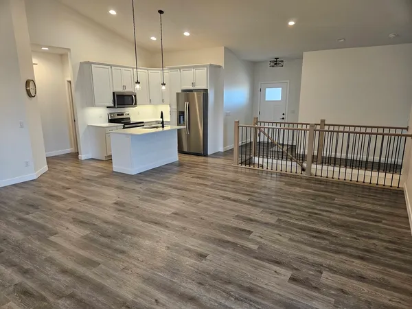 a large kitchen with stainless steel appliances a large counter top and a wooden floors