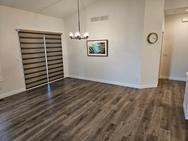 an empty room with wooden floor chandelier and windows