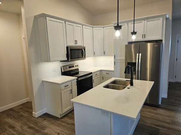 a kitchen with kitchen island a sink appliances and wooden floor