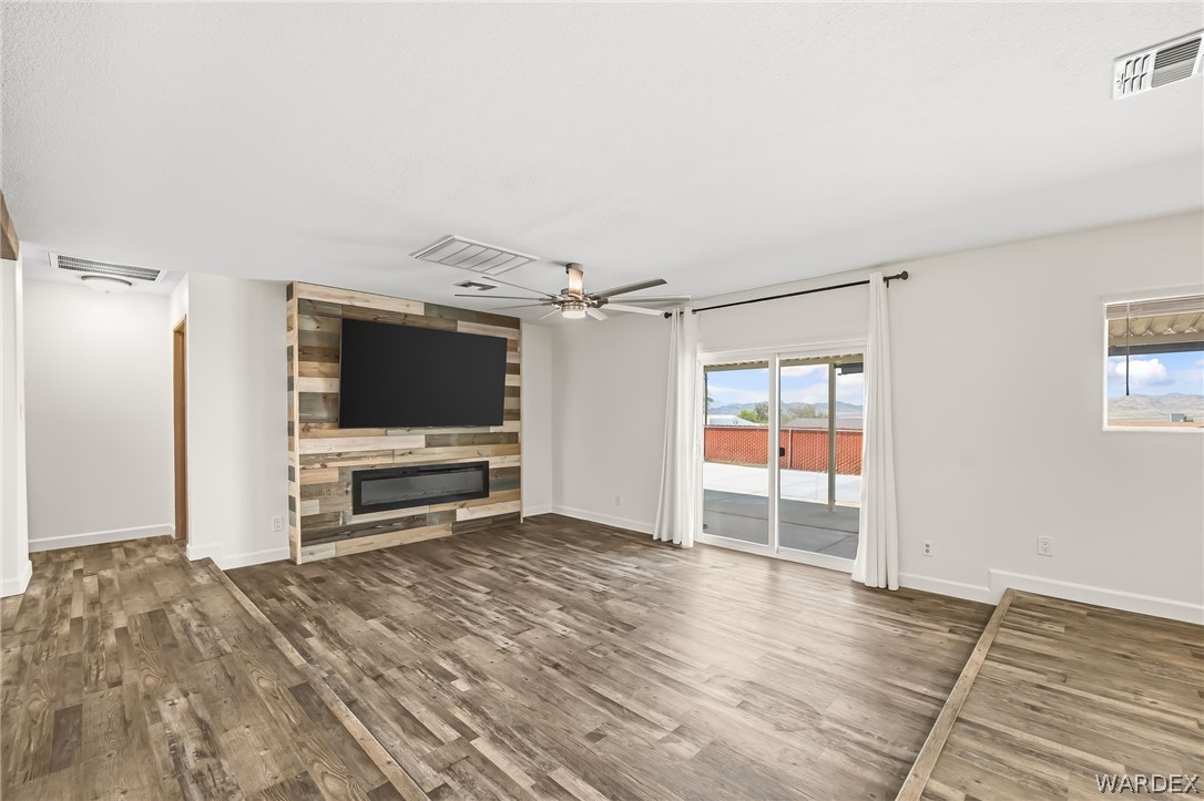 4088 Mercer Road Bullhead City, AZ 86429 - Photo 7 of 35 Spacious living area featuring wood-finish flooring, a decorative accent wall, and a built-in electric fireplace