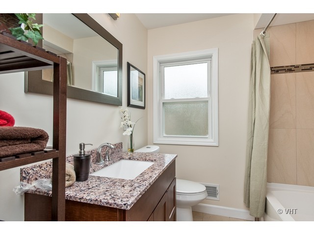 8500 Springfield Avenue Skokie, IL 60076 - Photo 13 of 15 a bathroom with a granite countertop sink toilet and mirror