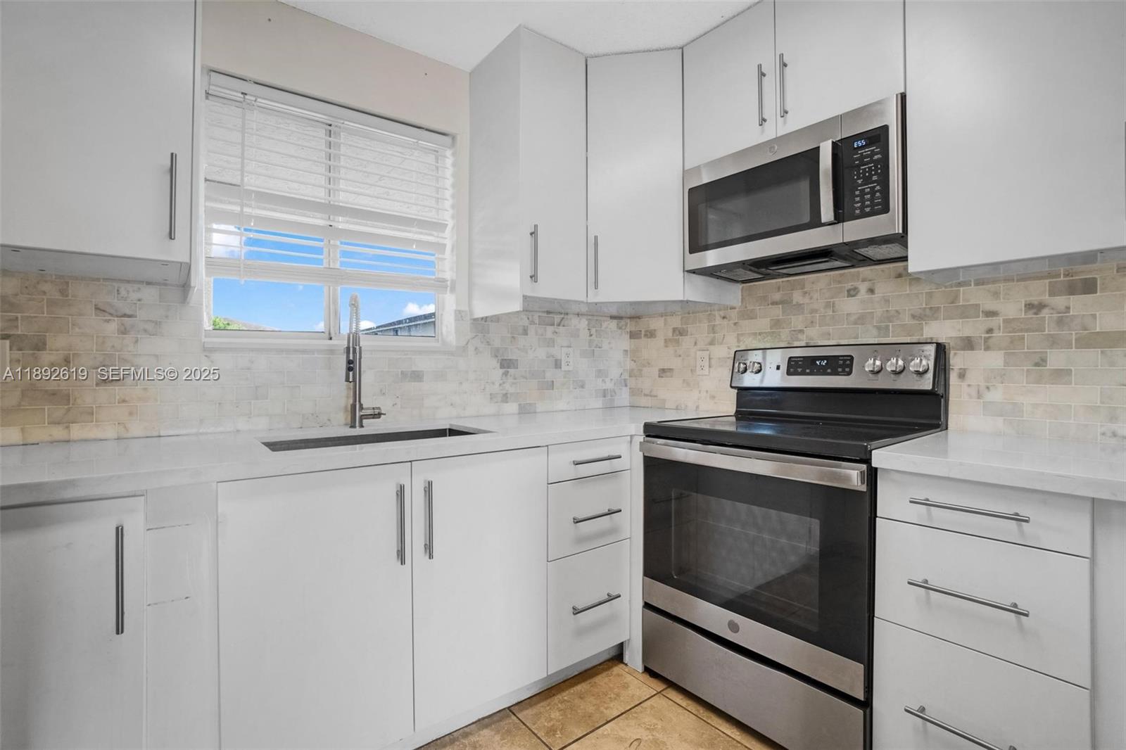 7785 West 30th Court, Unit F210 Hialeah, FL 33018 - Photo 3 of 21 a kitchen with white cabinets stainless steel appliances and sink