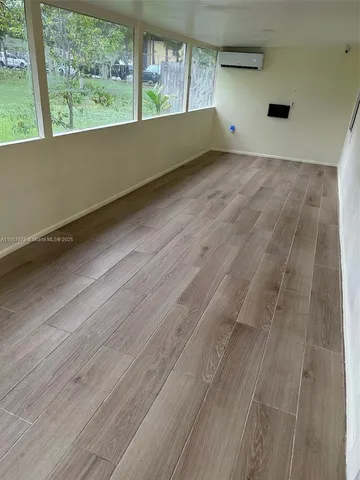 a view of an empty room with wooden floor and windows