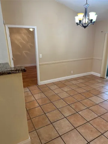 an empty room with kitchen and chandelier fan
