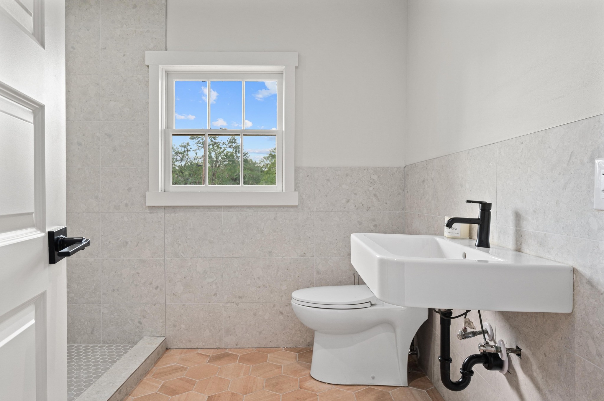 3501 Pecan Springs Road Austin, TX 78723 - Photo 30 of 40 Bathroom featuring tile walls, a stall shower, light tile patterned floors, and a wainscoted wall