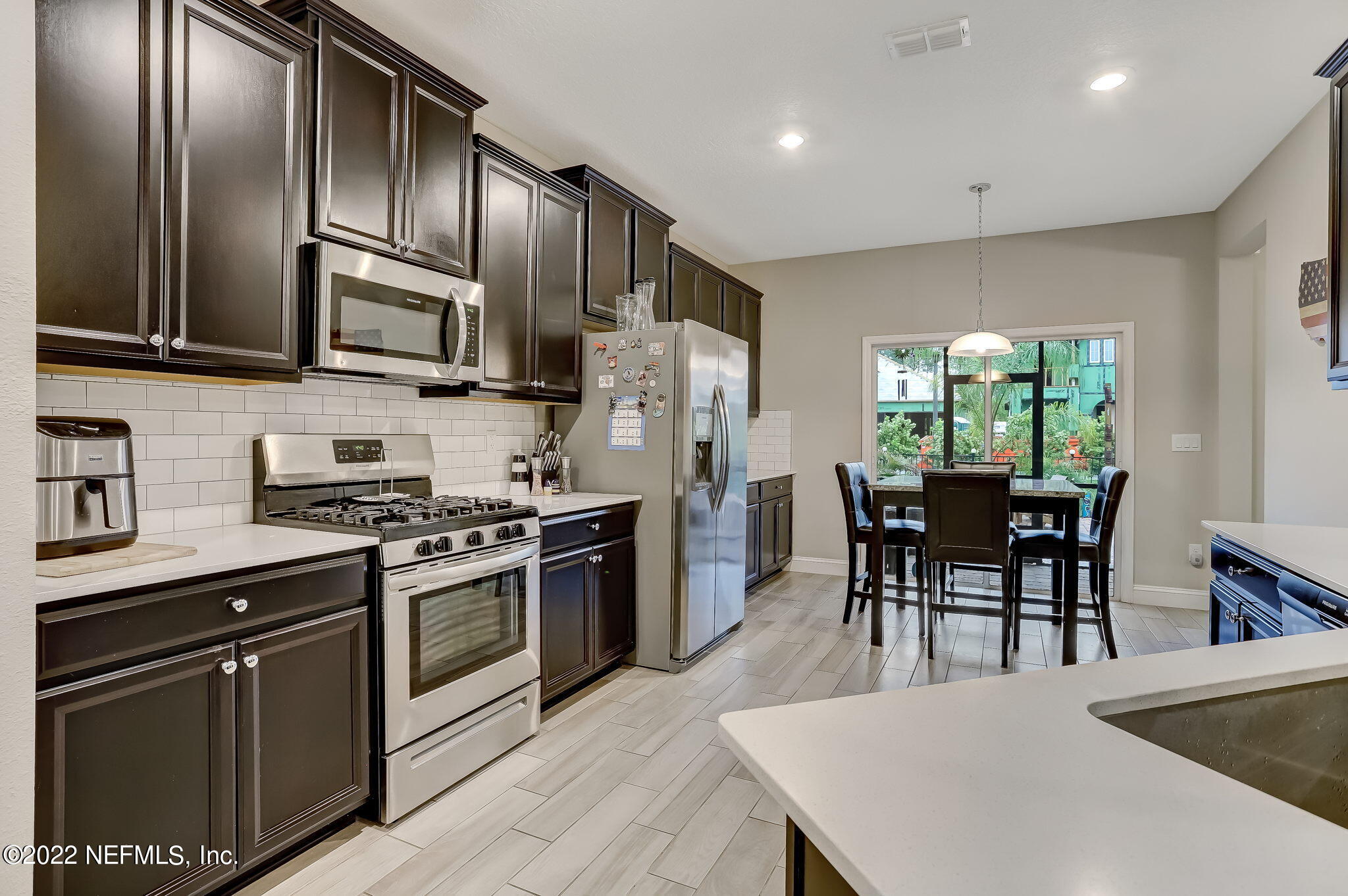 2564 Alexia Circle Jacksonville, FL 32246 - Photo 24 of 67 a kitchen with stainless steel appliances granite countertop a stove a refrigerator a kitchen island a stove a dining table and chairs with wooden floor