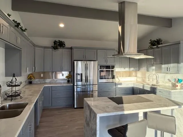 a kitchen with stainless steel appliances kitchen island granite countertop a sink refrigerator and cabinets