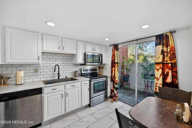 a kitchen with stainless steel appliances granite countertop a stove top oven a sink dishwasher and cabinets with wooden floor