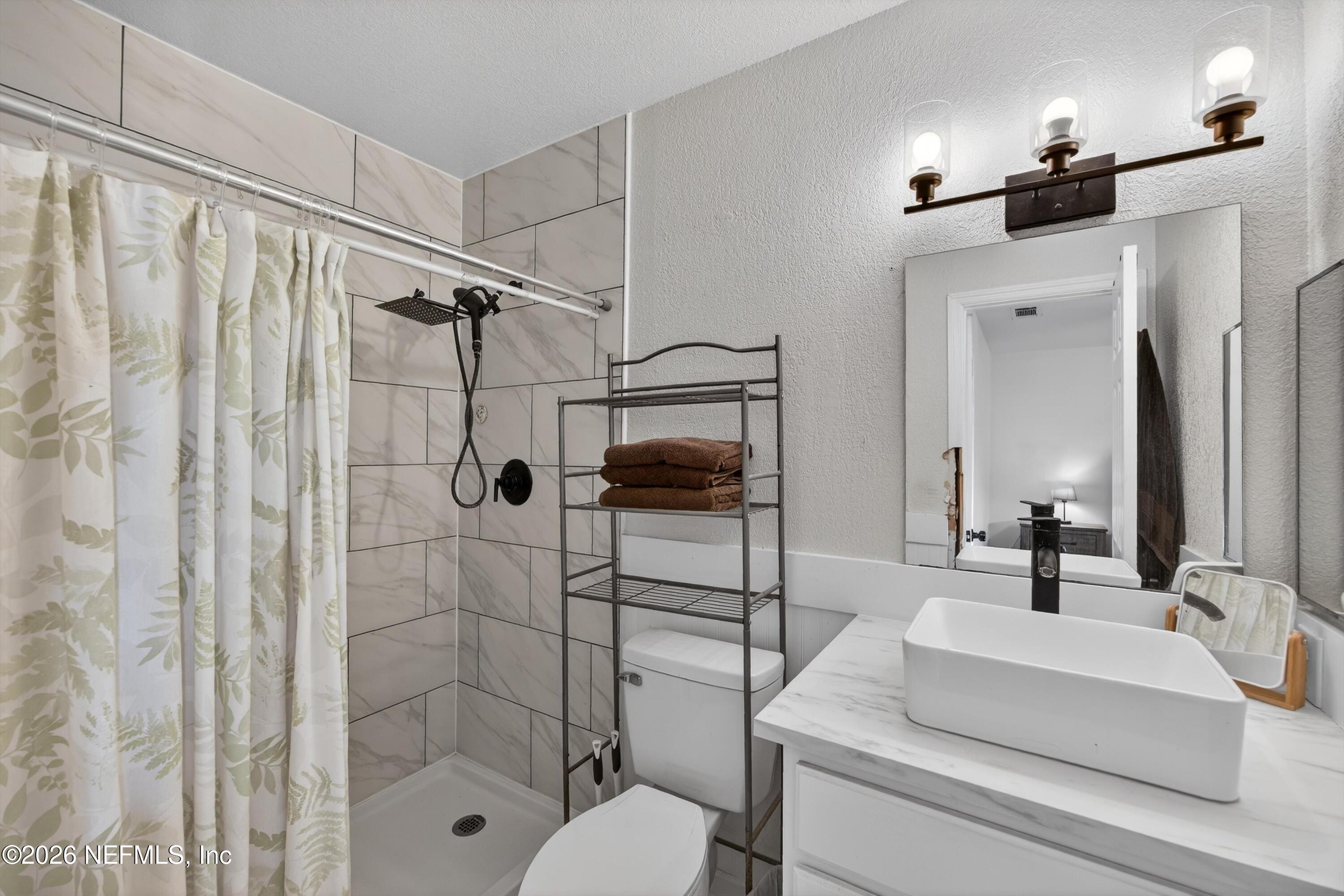 8880 Old Kings Road South, Unit 2 Jacksonville, FL 32257 - Photo 23 of 35 a bathroom with a sink toilet a mirror and shower