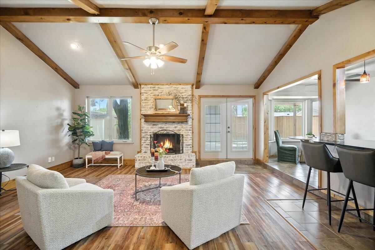 5726 67th Street Lubbock, TX 79424 - Photo 3 of 26 a living room with furniture a fireplace and a dining table with wooden floor
