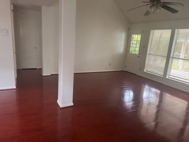 an empty room with wooden floor and windows