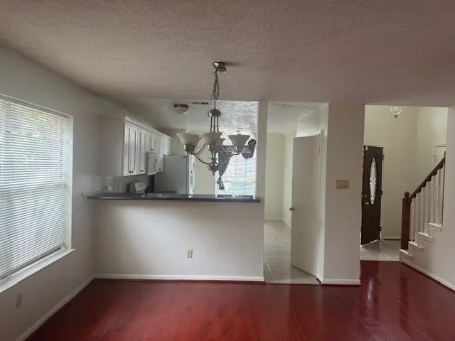 a view of a kitchen with a refrigerator wooden floor and a window