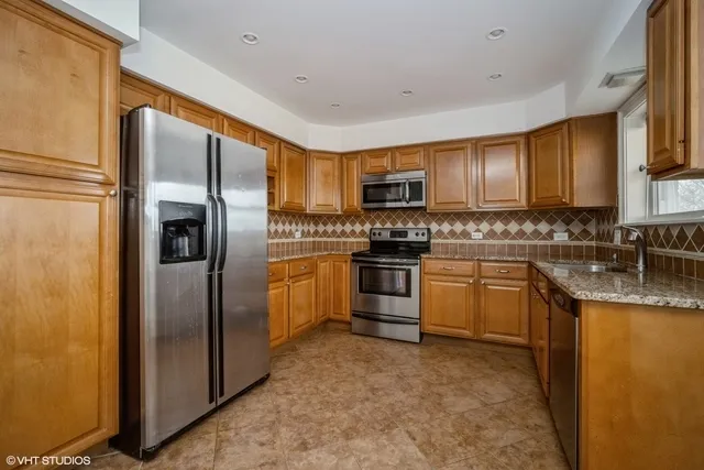 a kitchen with stainless steel appliances granite countertop a refrigerator sink and stove