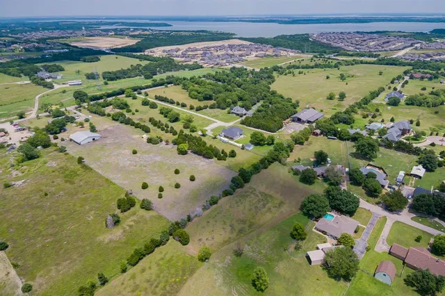 an aerial view of a residential houses with outdoor space and trees