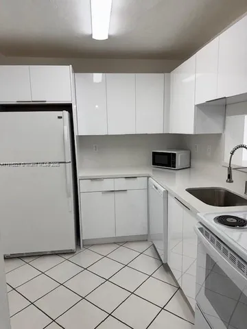 a kitchen with a sink a refrigerator and cabinets