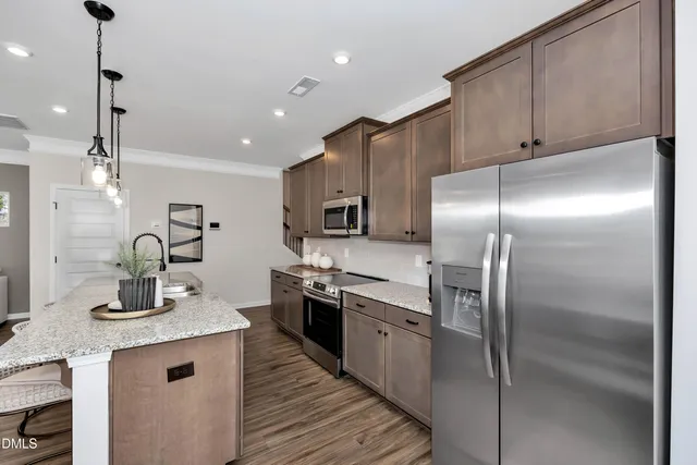 a kitchen with kitchen island a counter top space a sink stainless steel appliances and cabinets
