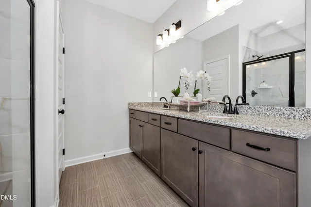 a bathroom with a granite countertop double vanity sink and mirror