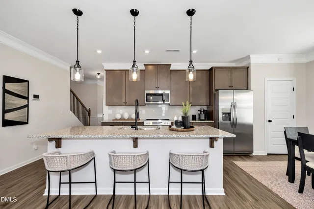 a kitchen with stainless steel appliances kitchen island granite countertop a dining table chairs and white cabinets