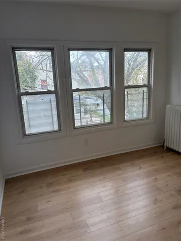 a view of an empty room with wooden floor and windows